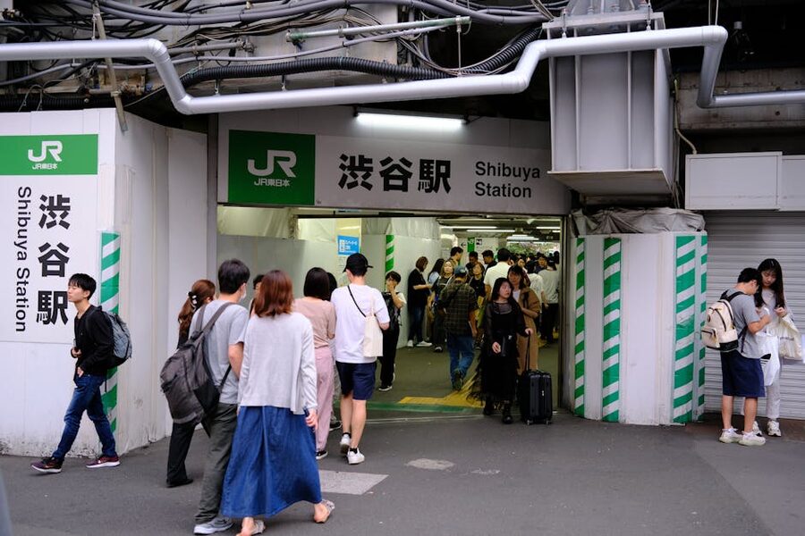 Shibuya Station entrance with pedestrians and signage at the Tokyu side