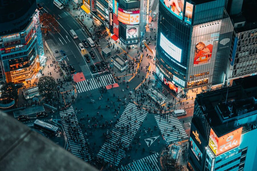 Aerial night view of Shibuya Crossing in Tokyo with neon-lit buildings and traffic