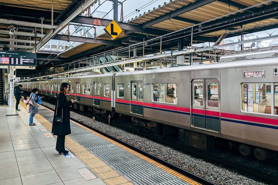 A train arriving at a Tokyo station platform with people waiting