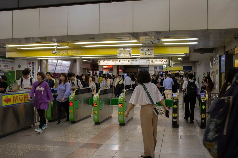 A crowded Tokyo subway station entrance with commuters passing through ticket gates