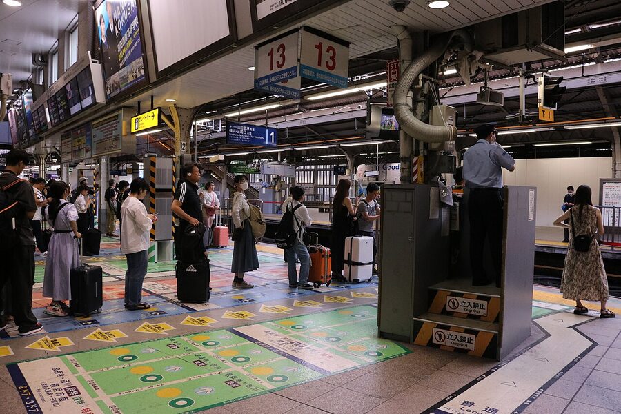 Keikyu Shinagawa platforms 1 and 2 during a Saturday-evening crush. The Keikyu section sits at the western edge of the S